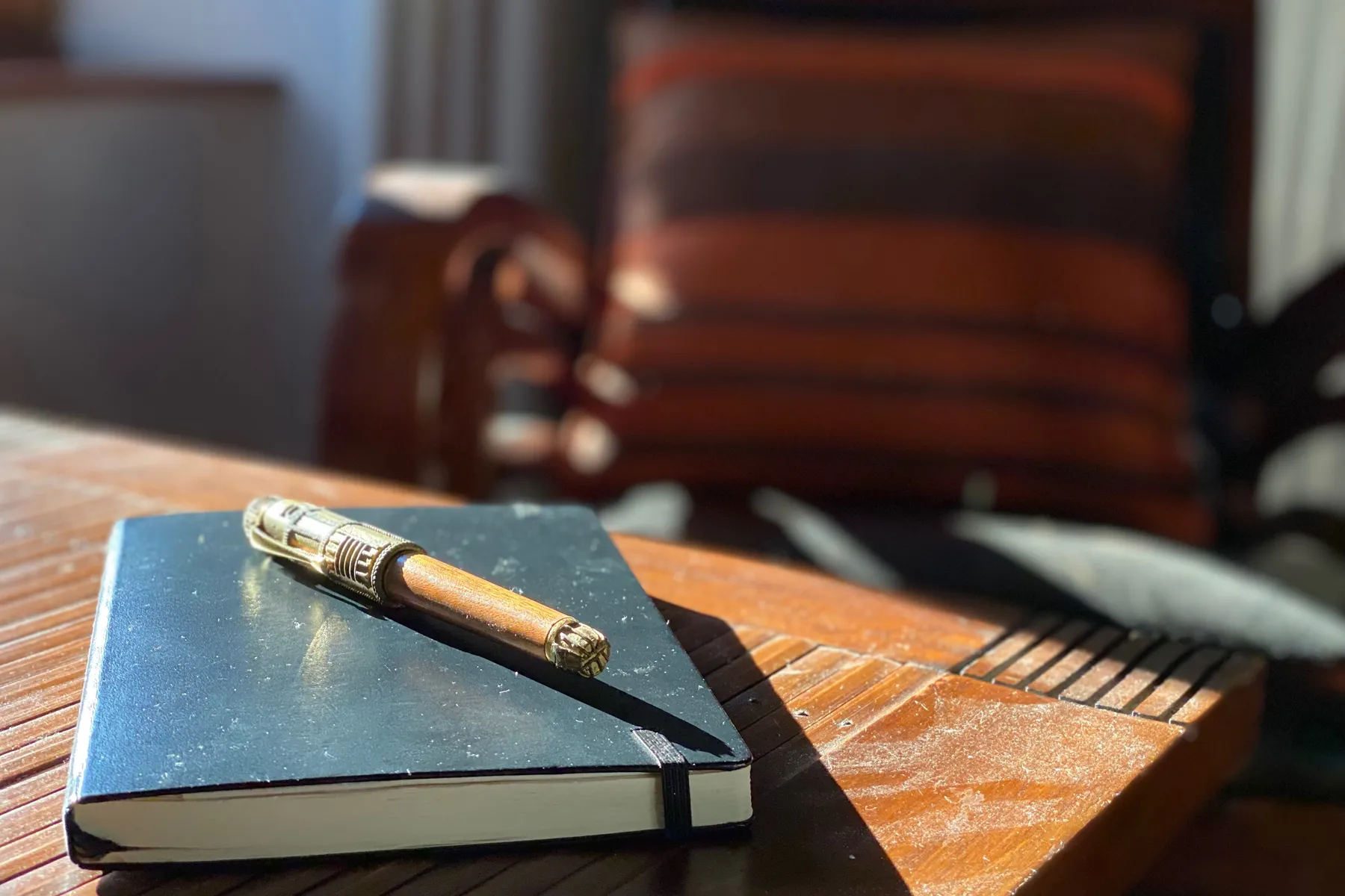 Un carnet et un stylo, posés au soleil sur une table en bois
